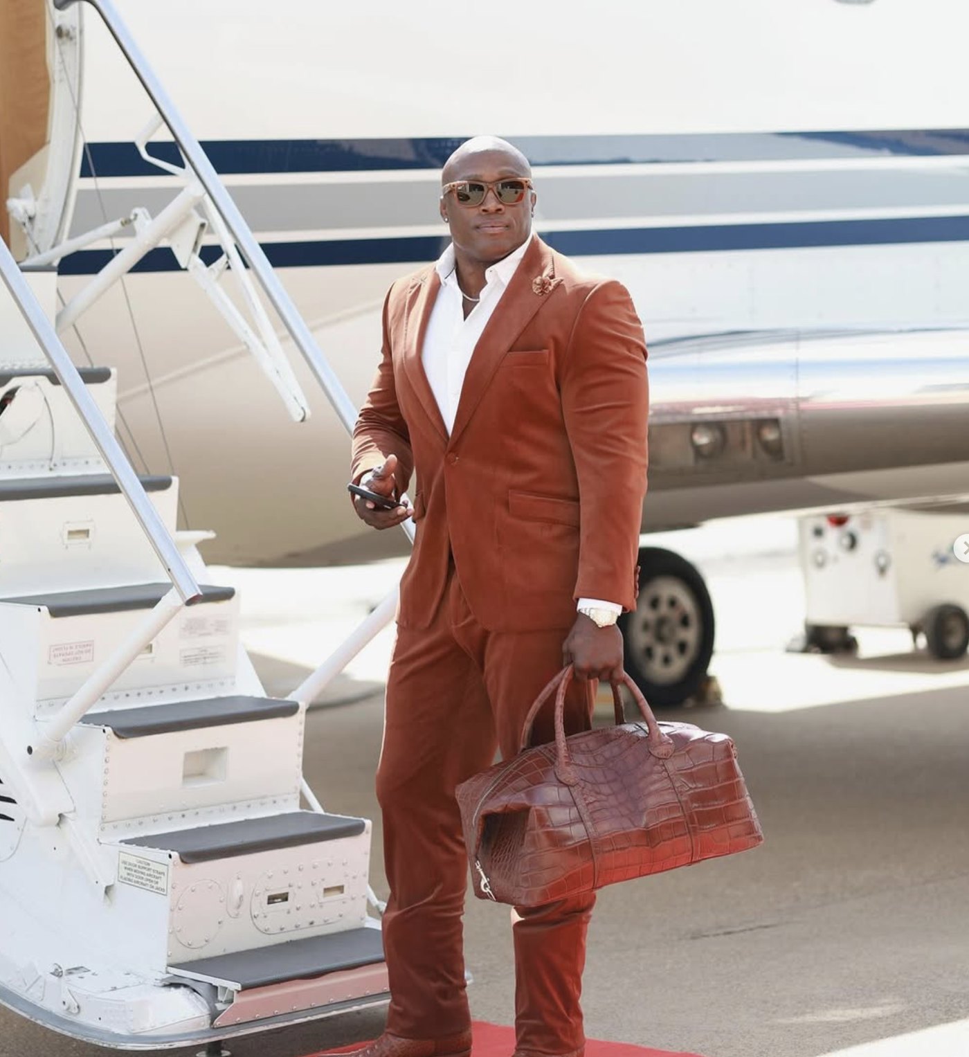 Bobby Lashley in a suit at the stairs of a private jet